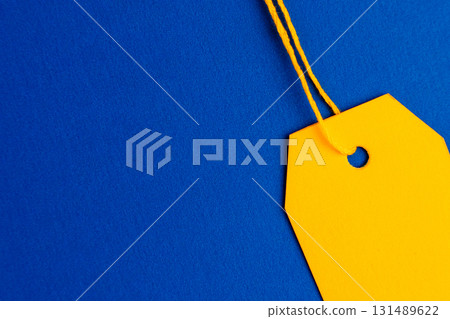 Close up yellow price tag on blue background with copy space 131489622