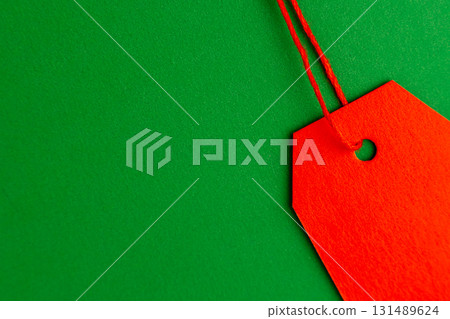 Red price tag on green background minimal top view 131489624
