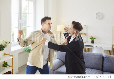 Two angry men shouting in an indoor conflict and arguing with fists raised Two angry men shouting in an indoor conflict and arguing with fists raised 131490971