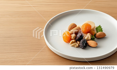 A colorful assortment of almonds, walnuts, and dried fruits arranged on a simple plate, ideal for a nutritious afternoon boost 131490979