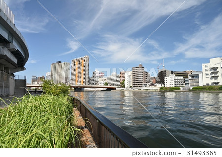 初秋的隅田川水流,以及蔚藍的秋日天空。高聳的天空和潔白的雲朵。對岸是公寓大樓和高速公路。 初秋的隅田川水流,以及蔚藍的秋日天空。高聳的天空和潔白的雲朵。對岸是公寓大樓和高速公路。 131493365