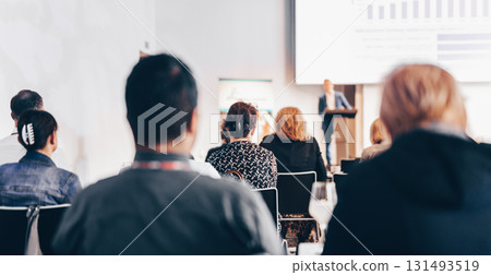 Speaker giving a talk in conference hall at business event. Rear view of unrecognizable people in audience at the conference hall. Business and entrepreneurship concept 131493519