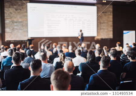 Speaker giving a talk in conference hall at business event. Rear view of unrecognizable people in audience at the conference hall. Business and entrepreneurship concept 131493534