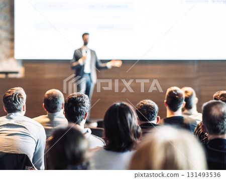 Speaker giving a talk in conference hall at business event. Rear view of unrecognizable people in audience at the conference hall. Business and entrepreneurship concept 131493536