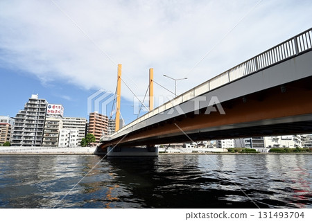 The flow of the Sumida River in early autumn. The view upstream of Shin-Ohashi Bridge. Apartment buildings on the opposite bank and the wide blue autumn sky and white clouds. 131493704