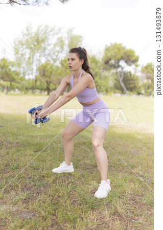 Young woman training with dumbbells doing outdoor fitness workout 131493879