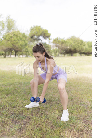 Woman exercising with dumbbells outdoors in park 131493880