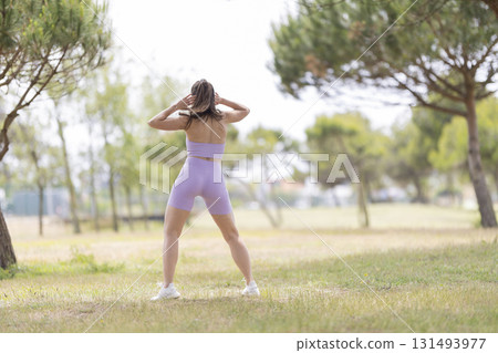 Woman exercising outdoors doing warm-up stretching in park 131493977