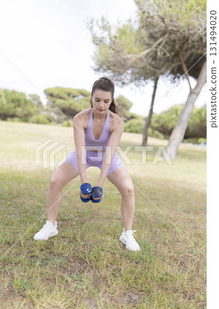 Young woman performing fitness workout with dumbbells 131494020