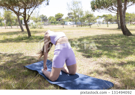 Woman practicing yoga camel pose outdoors on mat Woman practicing yoga camel pose outdoors on mat 131494092