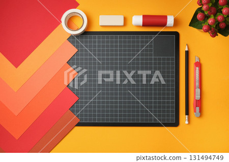Workspace for paper crafts. Sheets of colored paper, cutting mat, pencil, knife, glue, and eraser on a yellow background. Copyspace Workspace for paper crafts. Sheets of colored paper, cutting mat, pencil, knife, glue, and eraser on a yellow background. Copyspace 131494749