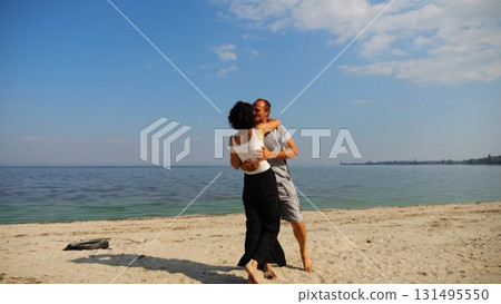 Happy couple spending time at sandy beach. Man kissing his beloved on seashore at sunny day. Carefree lovers resting during summer travel at coastline. Concept of vacation or holiday. Slow motion Happy couple spending time at sandy beach. Man kissing his beloved on seashore at sunny day. Carefree lovers resting during summer travel at coastline. Concept of vacation or holiday. Slow motion 131495550
