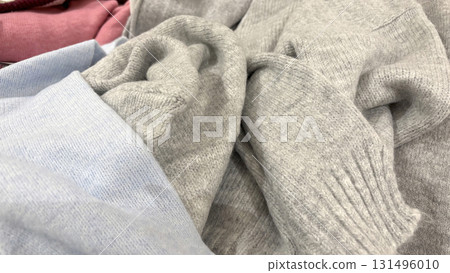 Warm knitted autumn and winter sweaters in a pile. Cozy seasonal clothing, casual fashion, soft knitwear, preparation for cold weather and wardrobe update 131496010