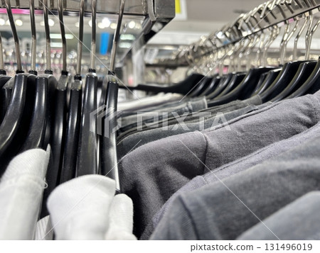 Casual t shirts hanging on hangers in clothing store. Wardrobe update, modern fashion, seasonal shopping, comfortable everyday apparel. Casual t shirts hanging on hangers in clothing store. Wardrobe update, modern fashion, seasonal shopping, comfortable everyday apparel. 131496019