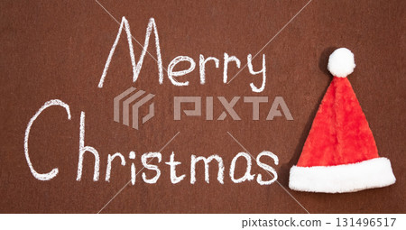 Merry Christmas handwritten in chalk next to Santa's hat 131496517