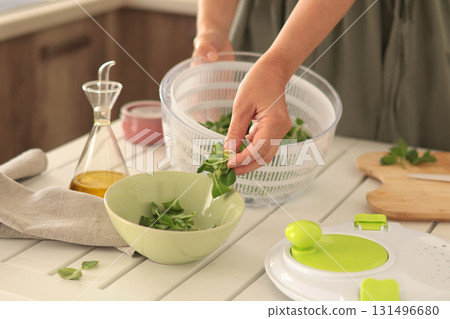 Woman put dried valerian leaves into bowl from dryer. Healthy eating and foods. Mediterranean diet. Woman put dried valerian leaves into bowl from dryer. Healthy eating and foods. Mediterranean diet. 131496680