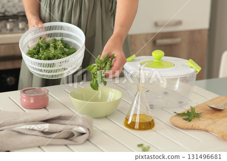 Woman put dried valerian leaves into bowl from dryer. Healthy eating and foods. Mediterranean diet.  131496681