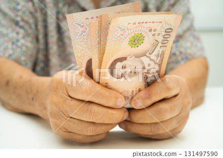 Asian elder senior woman patient holding Thai banknotes money in her hand, Cost of living and medical care. 131497590
