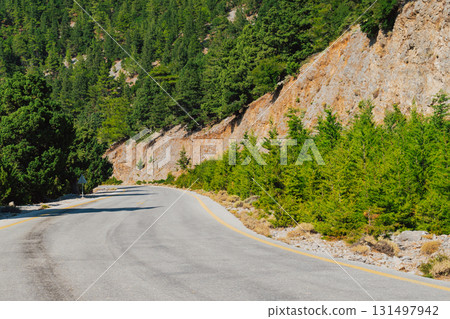 Mountain road section in Crete near Omalos in White Mountains with pine trees. Mountain road section in Crete near Omalos in White Mountains with pine trees. 131497942