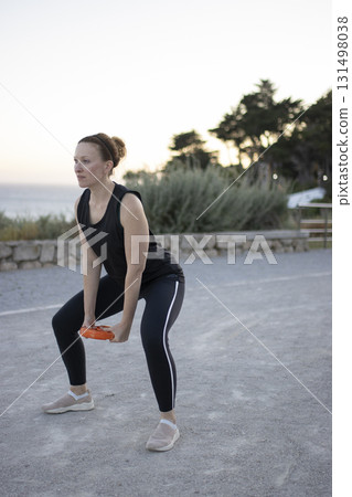 Woman squatting with weight training for fitness outdoors 131498038