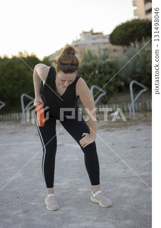 Woman experiencing knee pain during outdoor workout 131498046