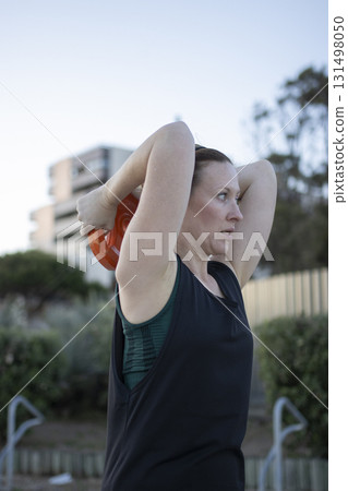 Woman exercising outdoors doing tricep extension with kettlebell Woman exercising outdoors doing tricep extension with kettlebell 131498050