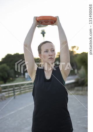 Woman training with weight plate overhead for fitness Woman training with weight plate overhead for fitness 131498068