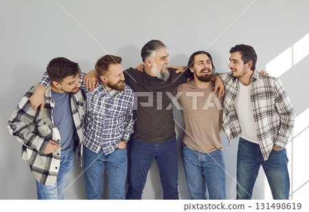 Male bearded friends looking cheerful to each other and smiling on grey wall background. Male bearded friends looking cheerful to each other and smiling on grey wall background. 131498619