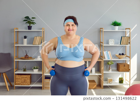 Fat funny woman looking at camera and doing sport exercises with dumbbells at home. Fat funny woman looking at camera and doing sport exercises with dumbbells at home. 131498622