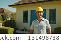 Man in yellow helmet standing in front of the house. He's wearing uniform and he's construction 131498738