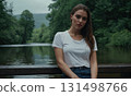 Young woman sitting on bench with her hair wet. She is wearing white T-shirt 131498766