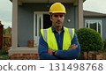 Man in yellow helmet standing in front of the house. He's wearing uniform and he's construction 131498768