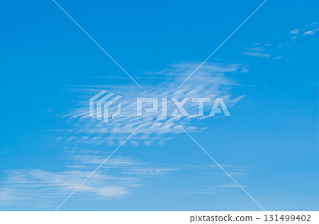 Background photo of a blue sky with wavy white clouds disintegrating under the influence of wind currents. Atmospheric phenomena in the upper layers. Natural surroundings Background photo of a blue sky with wavy white clouds disintegrating under the influence of wind currents. Atmospheric phenomena in the upper layers. Natural surroundings 131499402