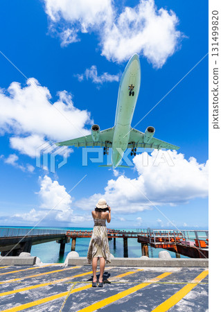 Miyako's spectacular view: A young woman and an airplane at 17 End Beach in front of Shimojishima Airport 131499820