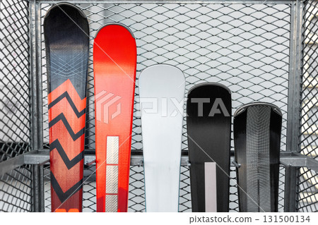New modern luxury premium red black white skis selection stored vertically in metal rack at alpine shop or rental at mountain ski resort winter season. Sport hobby equipment gear. Active lifestyle New modern luxury premium red black white skis selection stored vertically in metal rack at alpine shop or rental at mountain ski resort winter season. Sport hobby equipment gear. Active lifestyle 131500134