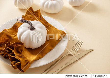 Autumn and Thanksgiving day table setting with plate decorated white pumpkins on beige table. Close up. Autumn and Thanksgiving day table setting with plate decorated white pumpkins on beige table. Close up. 131500643