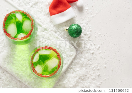 Xmas Green Punch in glass decorated sugar rim on white table make of cool lime sherbet. Tasty drink for Christmas holiday. Rim your festive beverages in red sugar. View from above. Xmas Green Punch in glass decorated sugar rim on white table make of cool lime sherbet. Tasty drink for Christmas holiday. Rim your festive beverages in red sugar. View from above. 131500652