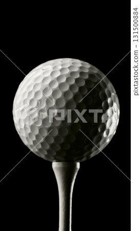 Close-up golf ball on tee in dramatic lighting against black background Close-up golf ball on tee in dramatic lighting against black background 131500884