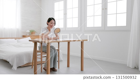 Middle-aged woman doing skin care while looking in the mirror Middle-aged woman doing skin care while looking in the mirror 131500932