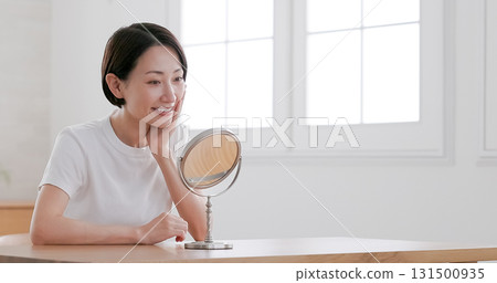 中年婦女一邊照鏡子一邊做皮膚護理 131500935