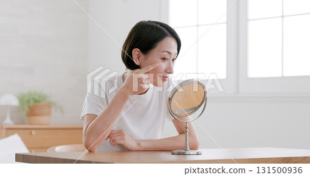 Middle-aged woman doing skin care while looking in the mirror Middle-aged woman doing skin care while looking in the mirror 131500936