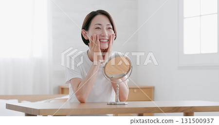 中年婦女一邊照鏡子一邊做皮膚護理 131500937
