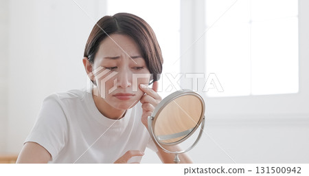 Middle-aged woman worried about her skin condition while looking in the mirror Middle-aged woman worried about her skin condition while looking in the mirror 131500942