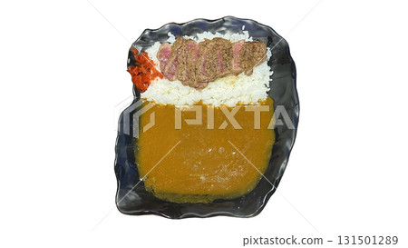 Traditional Japanese curry rice topped with sliced beef steak and red pickles served on a black plate. 131501289