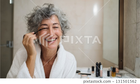 Smiling Older Woman Applying Makeup In Bathroom. Embracing Beauty And Self-Care At Any Age Smiling Older Woman Applying Makeup In Bathroom. Embracing Beauty And Self-Care At Any Age 131501562