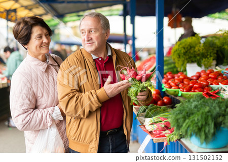 elderly man and woman buy radishes at an open market elderly man and woman buy radishes at an open market 131502152