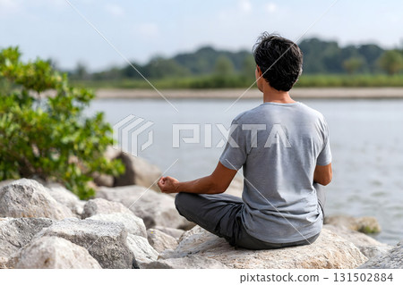 Man Meditating Outdoors by the River in Nature 131502884