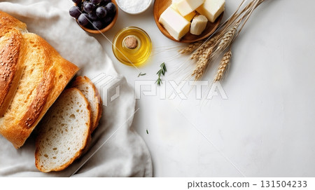 Fresh bread slices with butter, olive oil, grapes, and wheat on a table. 131504233