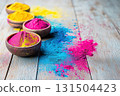 Bowls of colorful Holi powder scattered on wooden surface 131504423