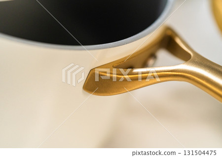 High-end golden handle on a glossy cream saucepan. Excellent for closeup product shots or online listings. 131504475